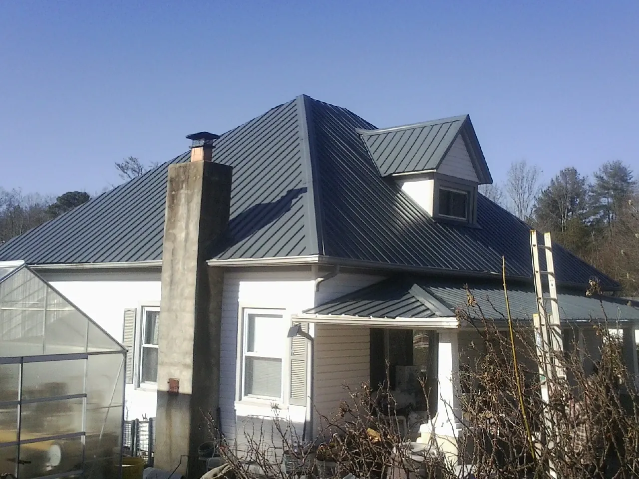 Dark blue standing seam metal roof on a white farmhouse with dormer — Slate & Tile Roof Repair by Roofing Brothers in Mars
