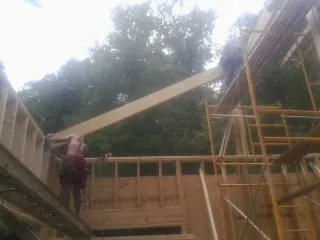 Carpenter raising a rafter beam on a new second story frame in Mars