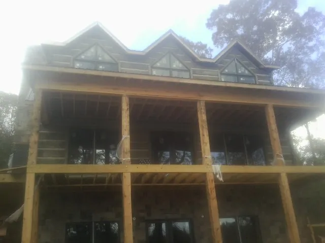 Dormers and porch framing on a large log home under construction — Roof Coating work by our crew in Mars