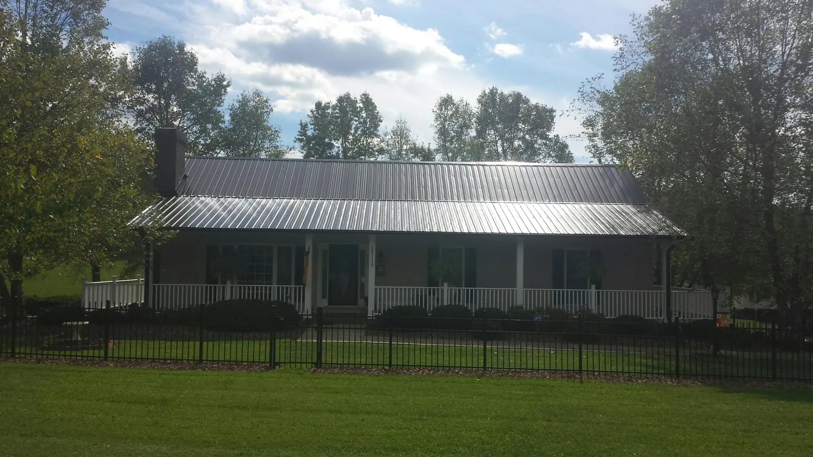 Gray metal roof on a brick ranch with a full width front porch — Gutter Guard Installation work by our crew in Mars