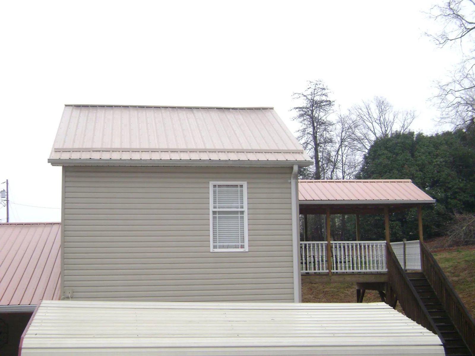 Tan metal roofs on a two story addition and attached porch, from a Roof Replacement job in Mars
