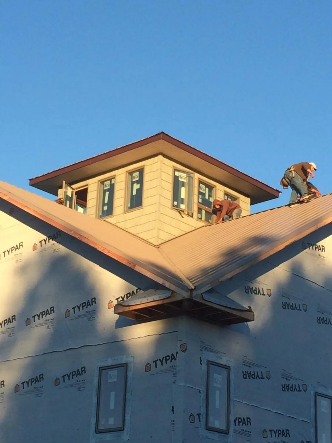 Roofers working around a rooftop cupola on a new metal roof at sunset — Roof Waterproofing in Mars by Roofing Brothers